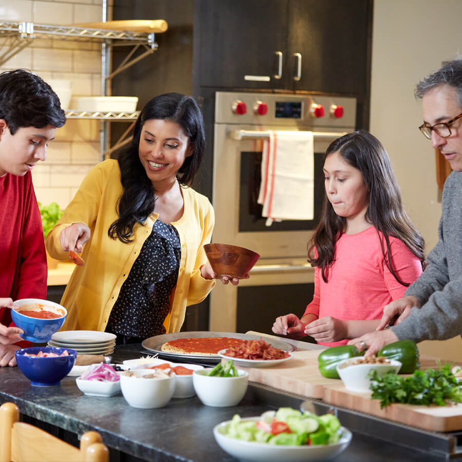 a hispanic family prepares a pizza dinner in their kitchen