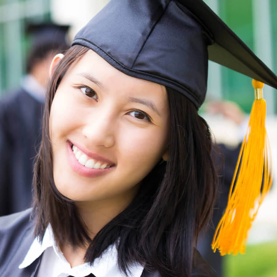 a closeup photo of a female student smiling in her cap and gown