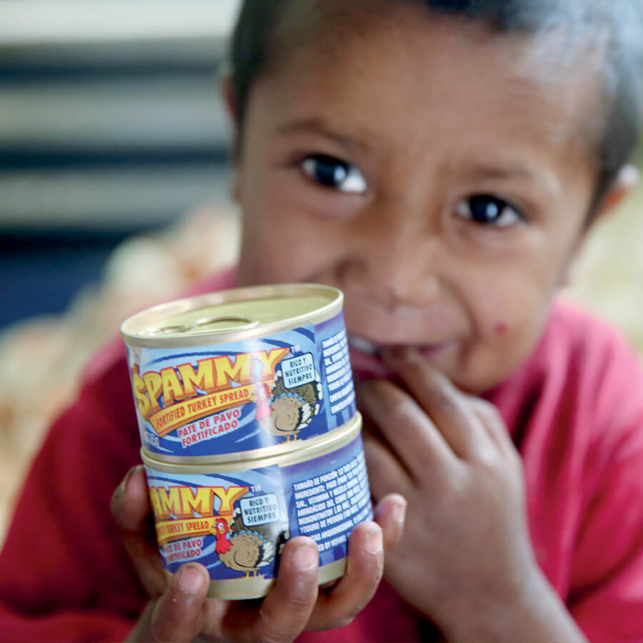 a Guatemalan child holds two cans of Spammy